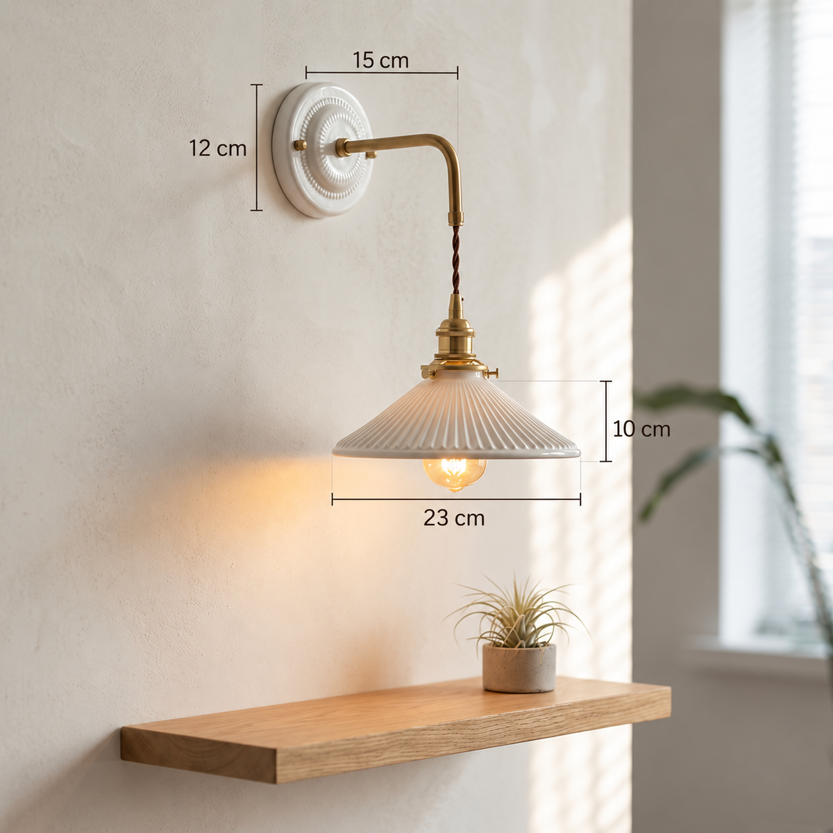 White ceramic wall sconce with brass hardware showing a 12 cm wall plate, 15 cm arm projection, 10 cm shade height and 23 cm shade width.