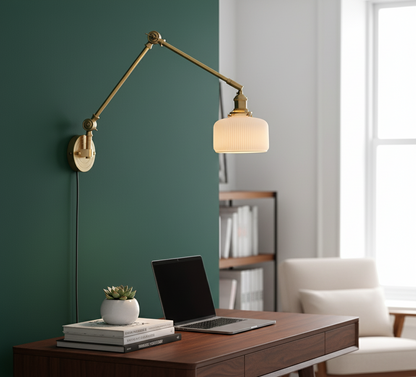 Wall-mounted lamp with a desk and laptop in a room with a green wall and white chair.