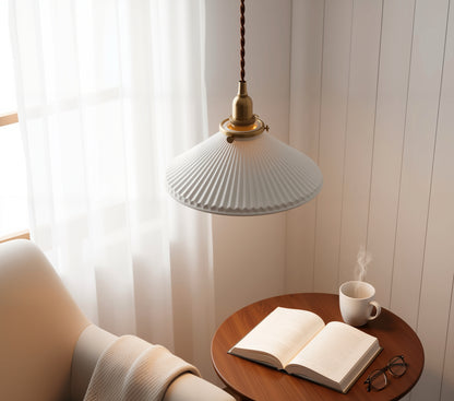 Pendant light over a wooden table with an open book and a cup of coffee.