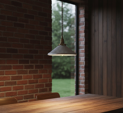 Pendant light hanging above a wooden table with a brick wall and window in the background