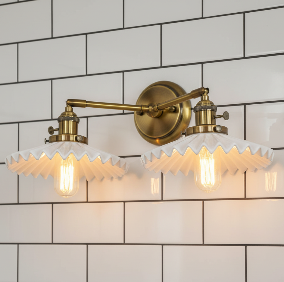 Double wall sconce with brass finish and white glass shades on a tiled wall.