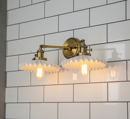 Gold wall sconce with glass shades against a white tiled wall