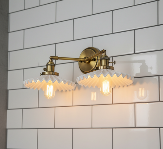 Gold wall sconce with glass shades against a white tiled wall