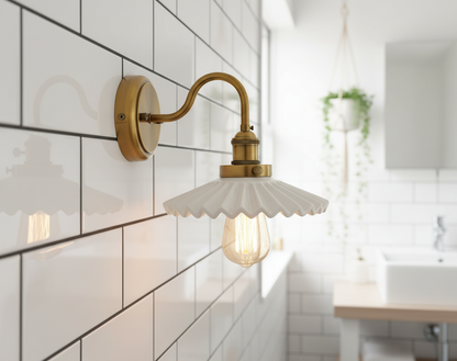 Wall-mounted brass light fixture with scalloped glass shade in a bathroom setting.