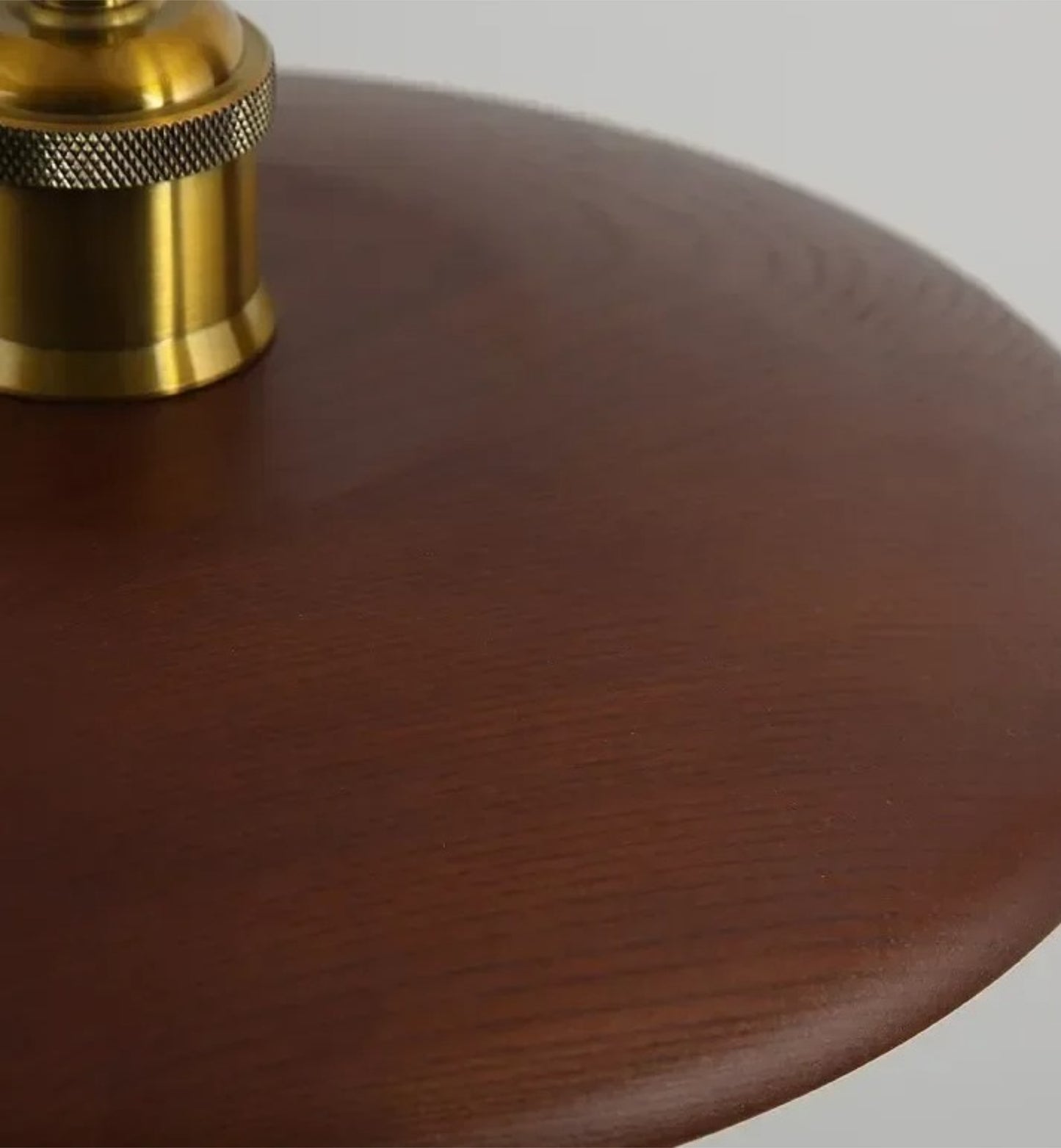 Close-up of a wooden lamp base with a brass fitting on a gray background