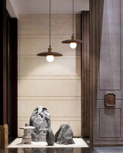 Modern interior with pendant lights, stone sculptures, and a wooden door.