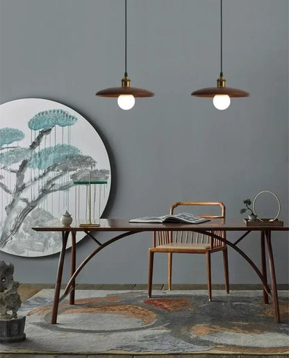 Modern dining room with wooden table, chairs, and hanging lights against a gray wall.