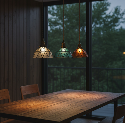Three colorful pendant lights hanging above a wooden table with a blurred outdoor background.