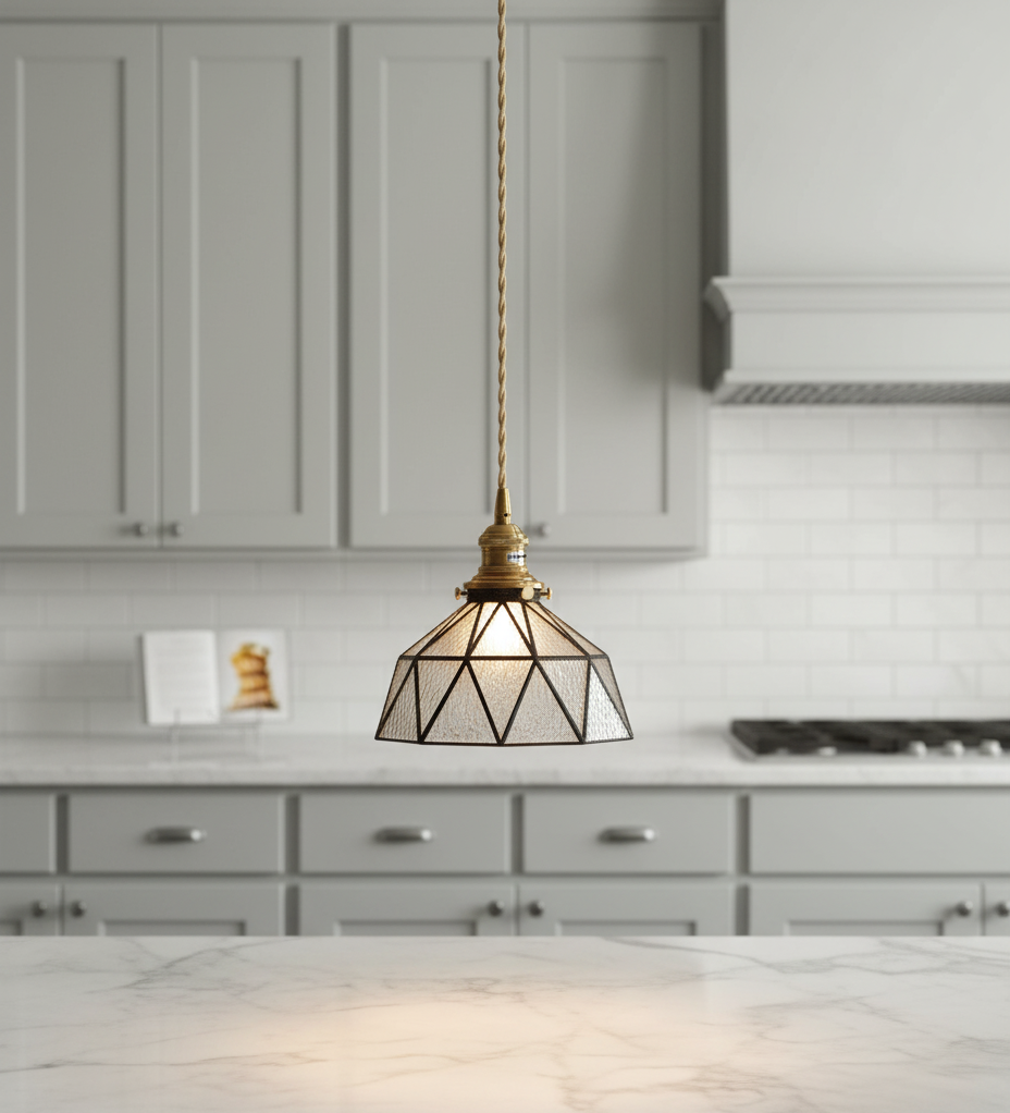 Geometric pendant light hanging in a kitchen with gray cabinets and white countertops.