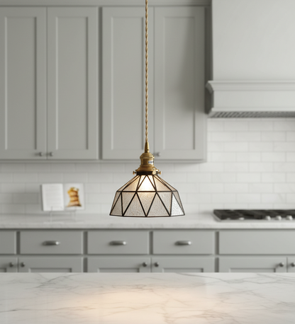 Geometric pendant light hanging in a kitchen with gray cabinets and white countertops.