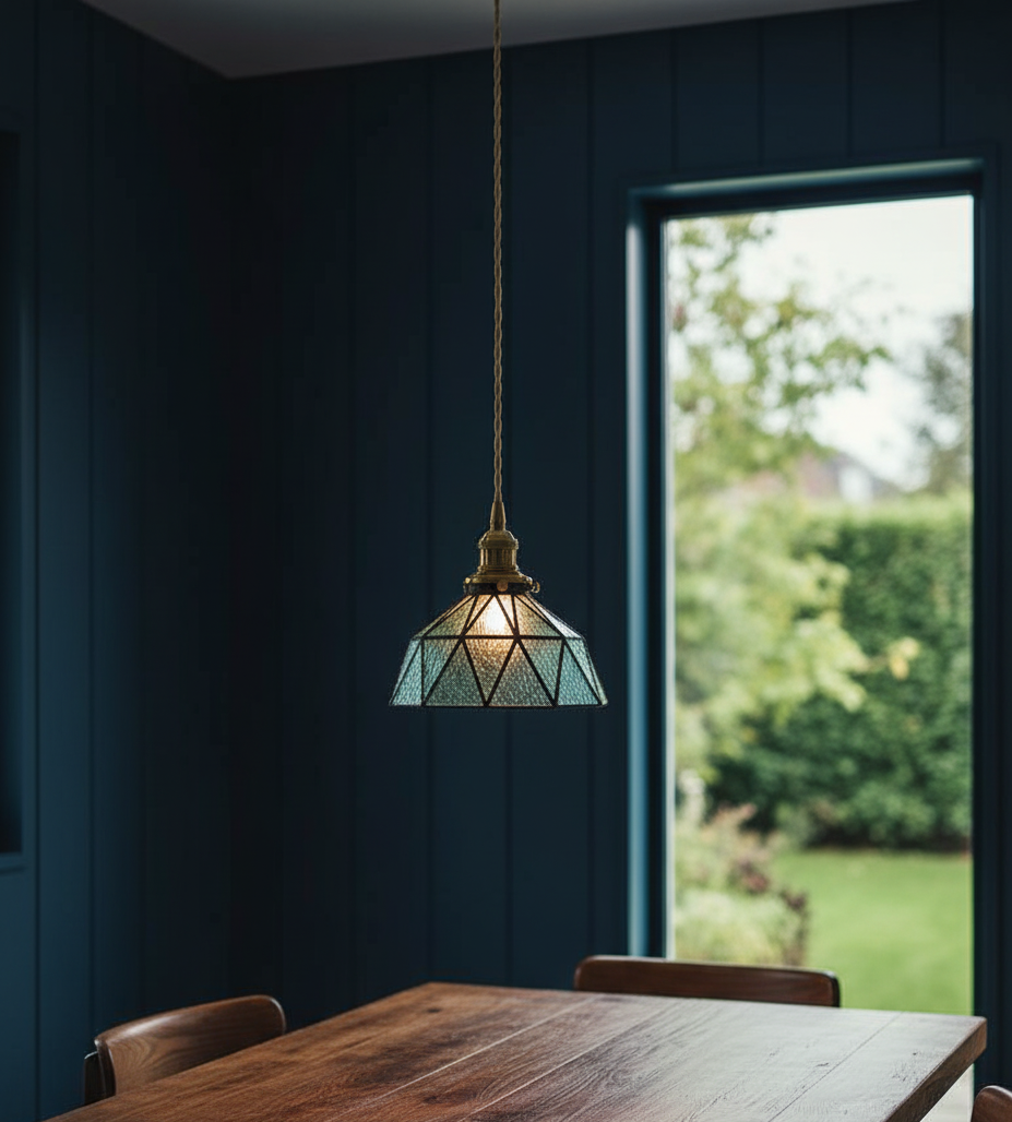 Pendant light hanging above a wooden table with a garden view in the background
